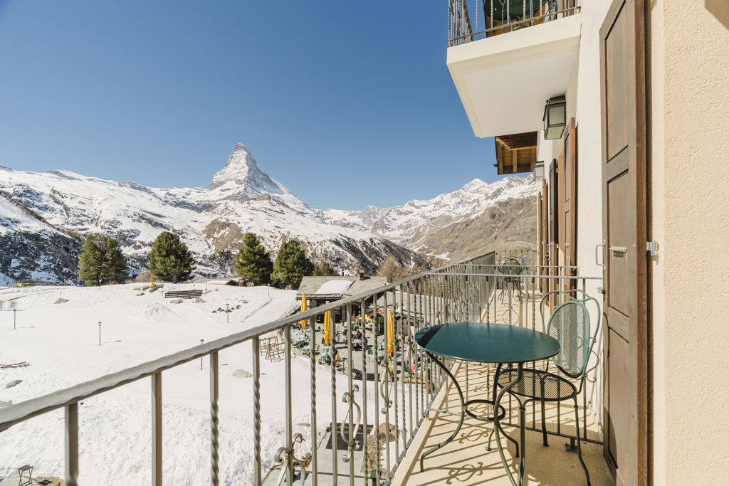 Vue panoramique sur le Cervin depuis le balcon aménagé de la Chambre Matterhorn Classic en hiver au Riffelalp Resort 2222m à Zermatt, hébergement chaleureux avec petit-déjeuner et accès au Spa 2222m inclus.