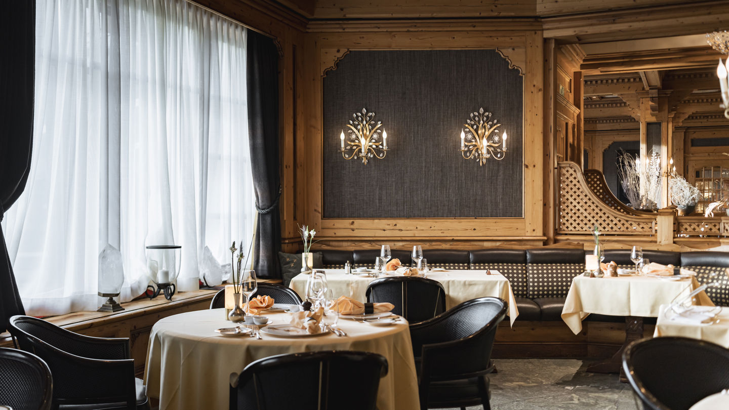 Salle lumineuse du Restaurant Alexandre en été au Riffelalp Resort 2222m à Zermatt, hôtel de luxe 5 étoiles dans les Alpes suisses, avec tables dressées, boiseries élégantes et atmosphère romantique pour un dîner gastronomique.