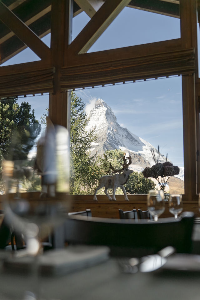 Table dressée devant une baie vitrée avec panorama sur le Matterhorn au Ristorante Al Bosco du Riffelalp Resort 2222m à Zermatt, hôtel de luxe 5 étoiles dans les Alpes suisses, proposant une expérience gastronomique italienne dans un cadre alpin d'exception.