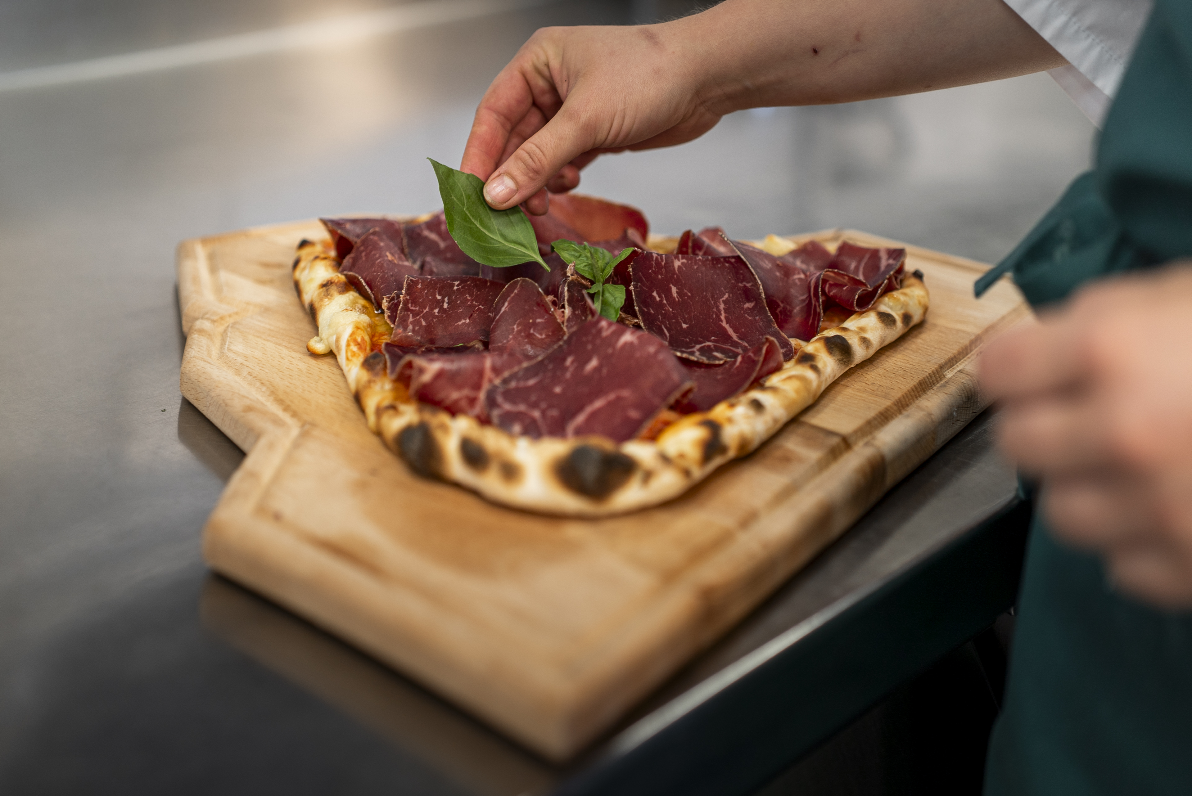 Chef préparant une pizza artisanale au Riffelalp Resort 2222m au-dessus de Zermatt, hôtel de luxe 5 étoiles dans les Alpes suisses offrant une cuisine italienne authentique et des spécialités préparées avec des ingrédients de qualité.