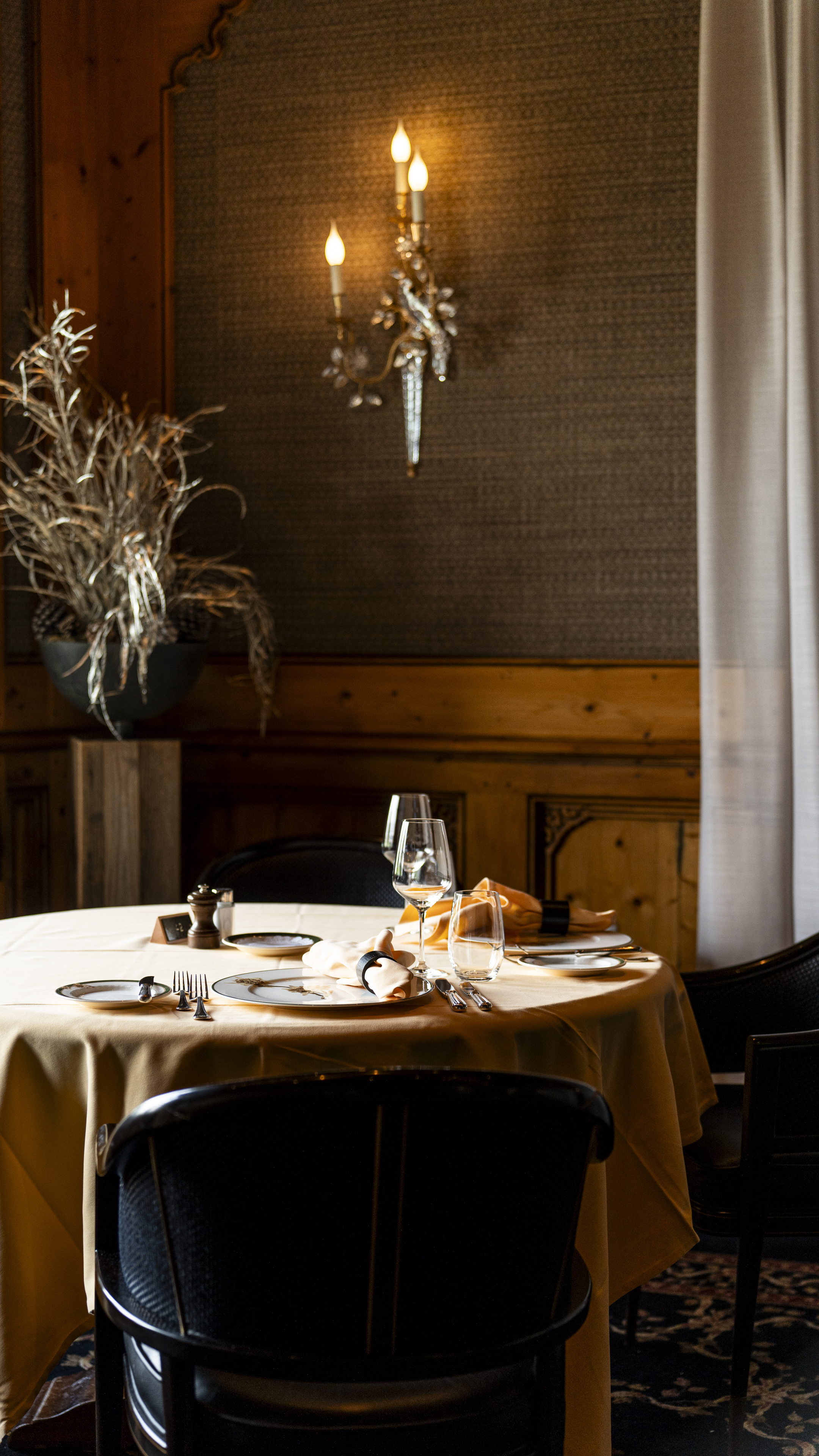 Table élégamment dressée aux chandelles dans la salle du Restaurant Alexandre en été au Riffelalp Resort 2222m à Zermatt, hôtel de luxe 5 étoiles offrant un dîner romantique dans une atmosphère alpine intime et raffinée.