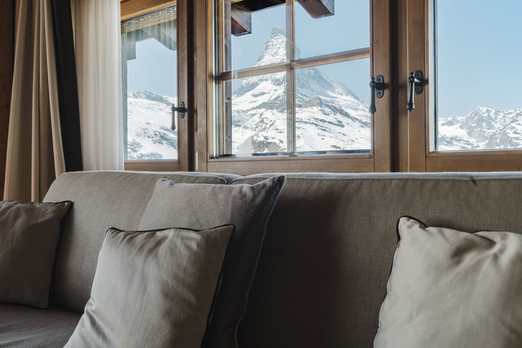 Vue rapprochée depuis le salon de la Suite Matterhorn, avec canapé au premier plan et Cervin enneigé encadré par les fenêtres.