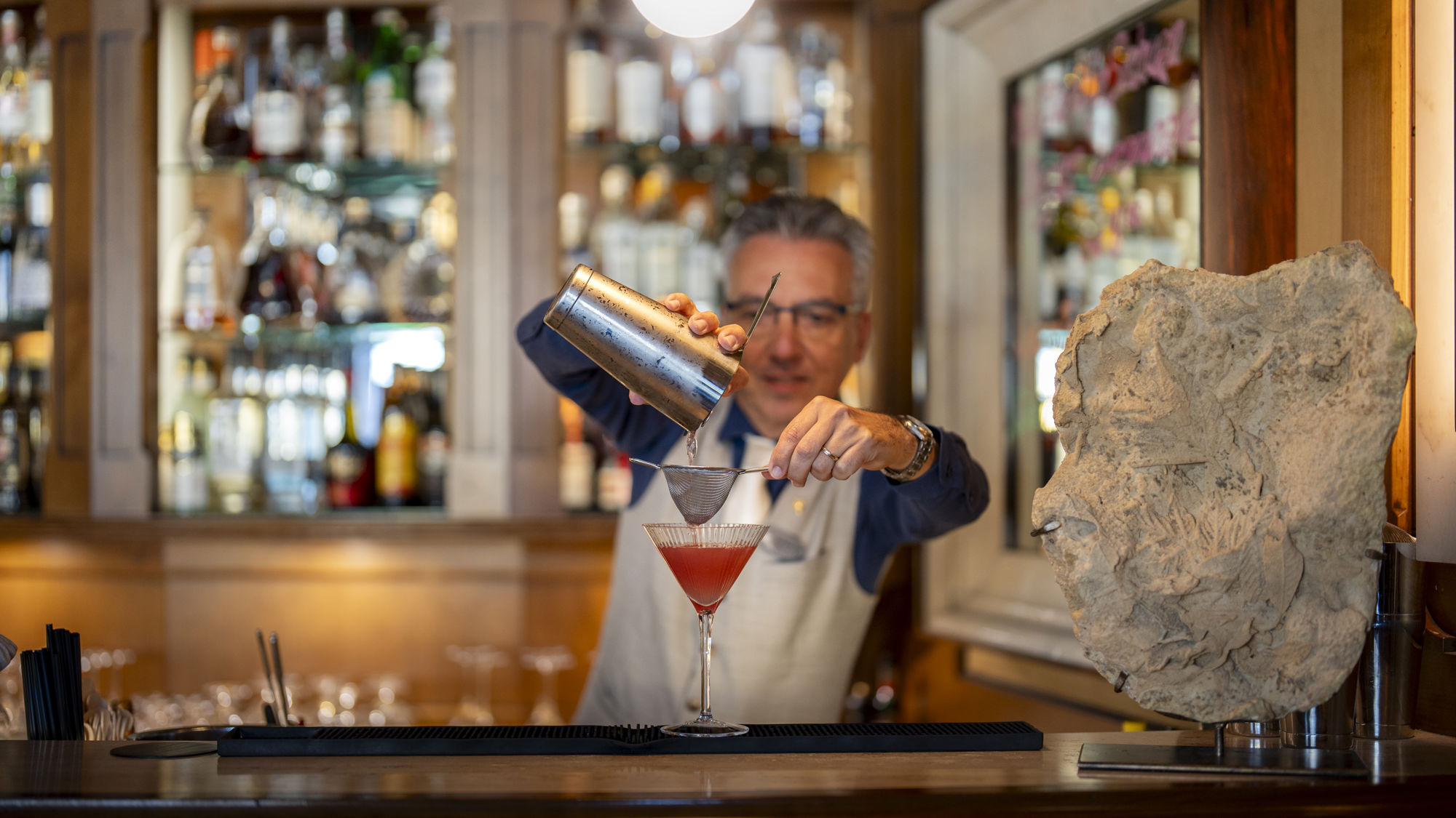 Chef barman du Riffelalp Resort 2222m à Zermatt préparant des cocktails signature, incarnant le savoir-faire, l'élégance et l'expérience d'un hôtel de luxe membre de The Leading Hotels of the World.