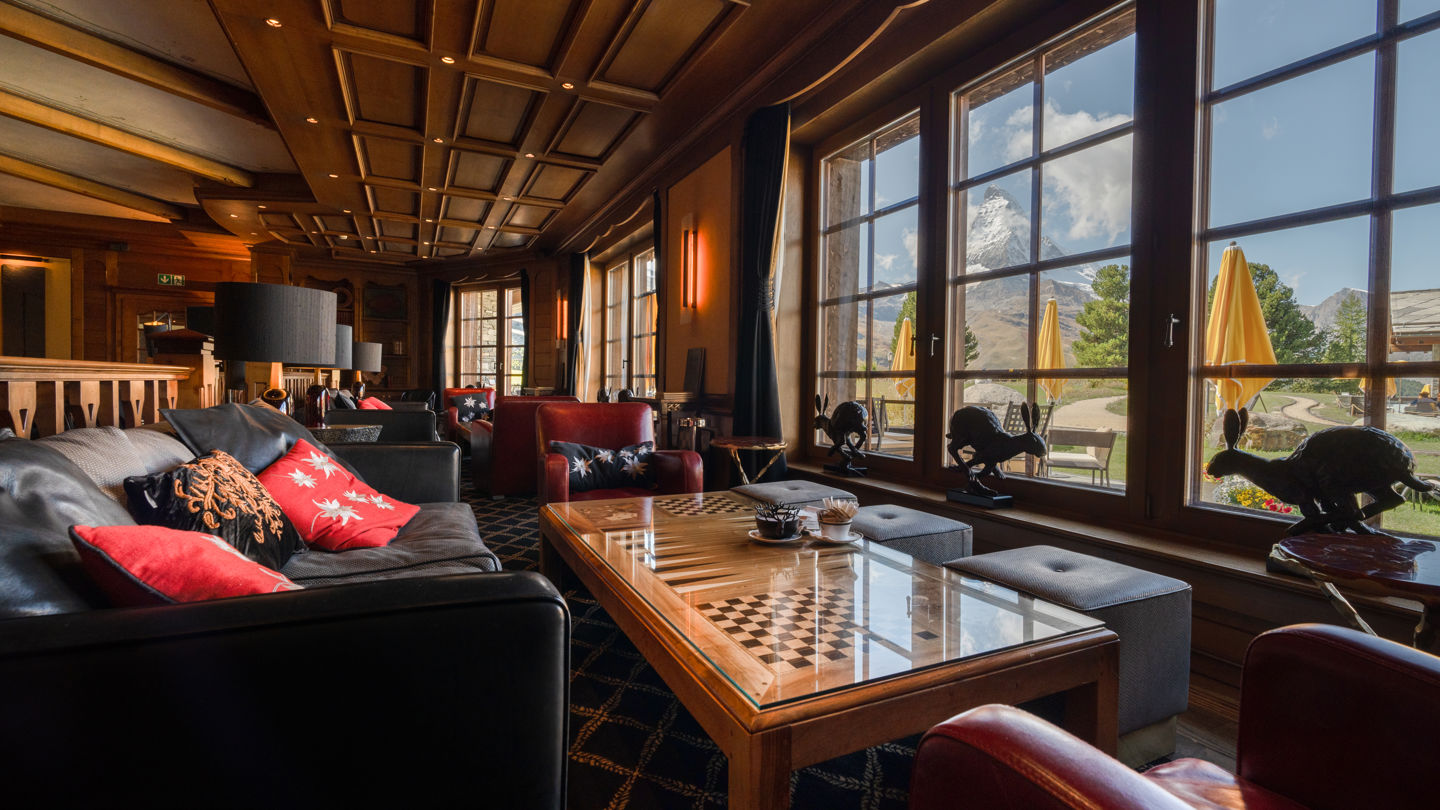 Espace lounge du Bar 2222m baigné de lumière au Riffelalp Resort 2222m à Zermatt, hôtel de luxe 5 étoiles dans les Alpes suisses proposant une ambiance élégante, une vue panoramique sur les Alpes et un cadre idéal pour se détendre en été.