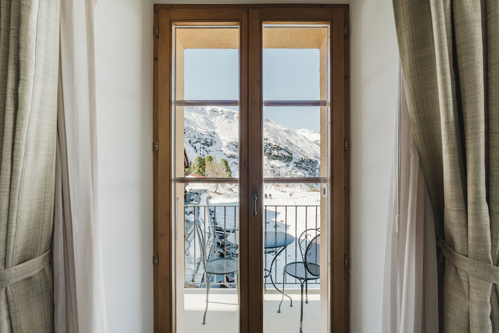 Vue sur le balcon et les montagnes enneigées depuis la Chambre NATUR Grandlit en hiver au Riffelalp Resort 2222m à Zermatt, hébergement chaleureux avec petit-déjeuner et accès au Spa 2222m inclus.