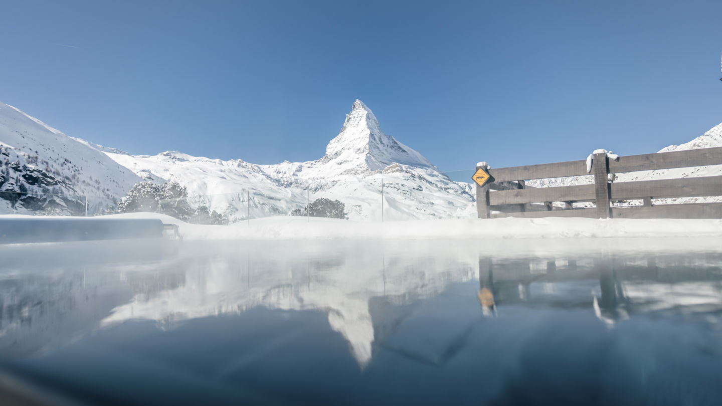 Reflets du Cervin dans la piscine extérieure chauffée en hiver du Spa 2222m au Riffelalp Resort 2222m à Zermatt, panorama emblématique du plus haut spa d'Europe.