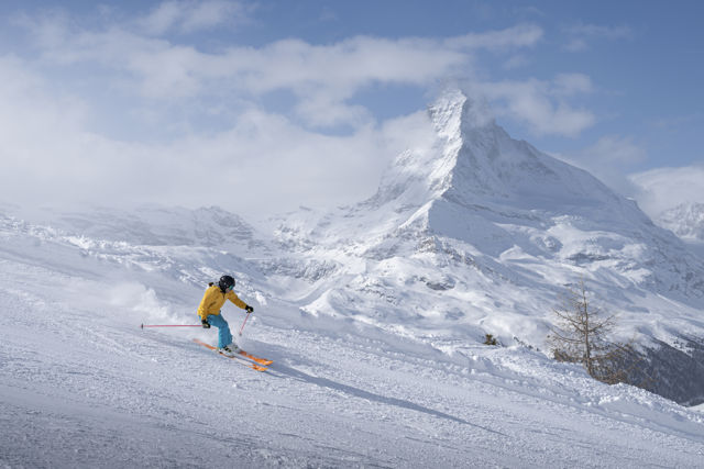 Skieur profitant des pistes enneigées avec panorama sur le Cervin près du Riffelalp Resort 2222m à Zermatt, hôtel de luxe 5 étoiles dans les Alpes suisses pour des vacances d'hiver, un séjour ski premium et des expériences de montagne exclusives.