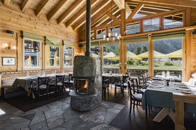 Salle lumineuse du Ristorante Al Bosco au Riffelalp Resort 2222m au-dessus de Zermatt, hôtel de luxe 5 étoiles dans les Alpes suisses, avec boiseries, grandes baies vitrées et ambiance de chalet pour un repas italien en montagne.