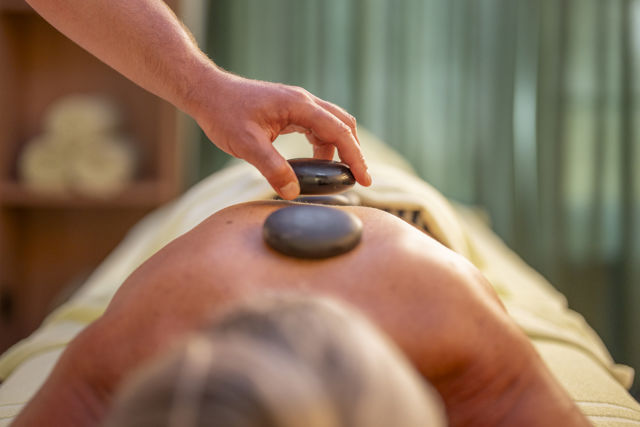 Massage aux pierres chaudes au Spa 2222m du Riffelalp Resort 2222m à Zermatt, soin relaxant inspiré des traditions alpines favorisant la récupération, le bien-être et la détente profonde.