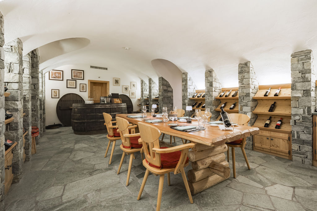Salle de dégustation de la Vinothek au Riffelalp Resort 2222m au-dessus de Zermatt, hôtel de luxe 5 étoiles dans les Alpes suisses, où les voûtes en pierre, les présentoirs à vins en bois et les grandes tables créent un cadre élégant pour une expérience œnologique raffinée.