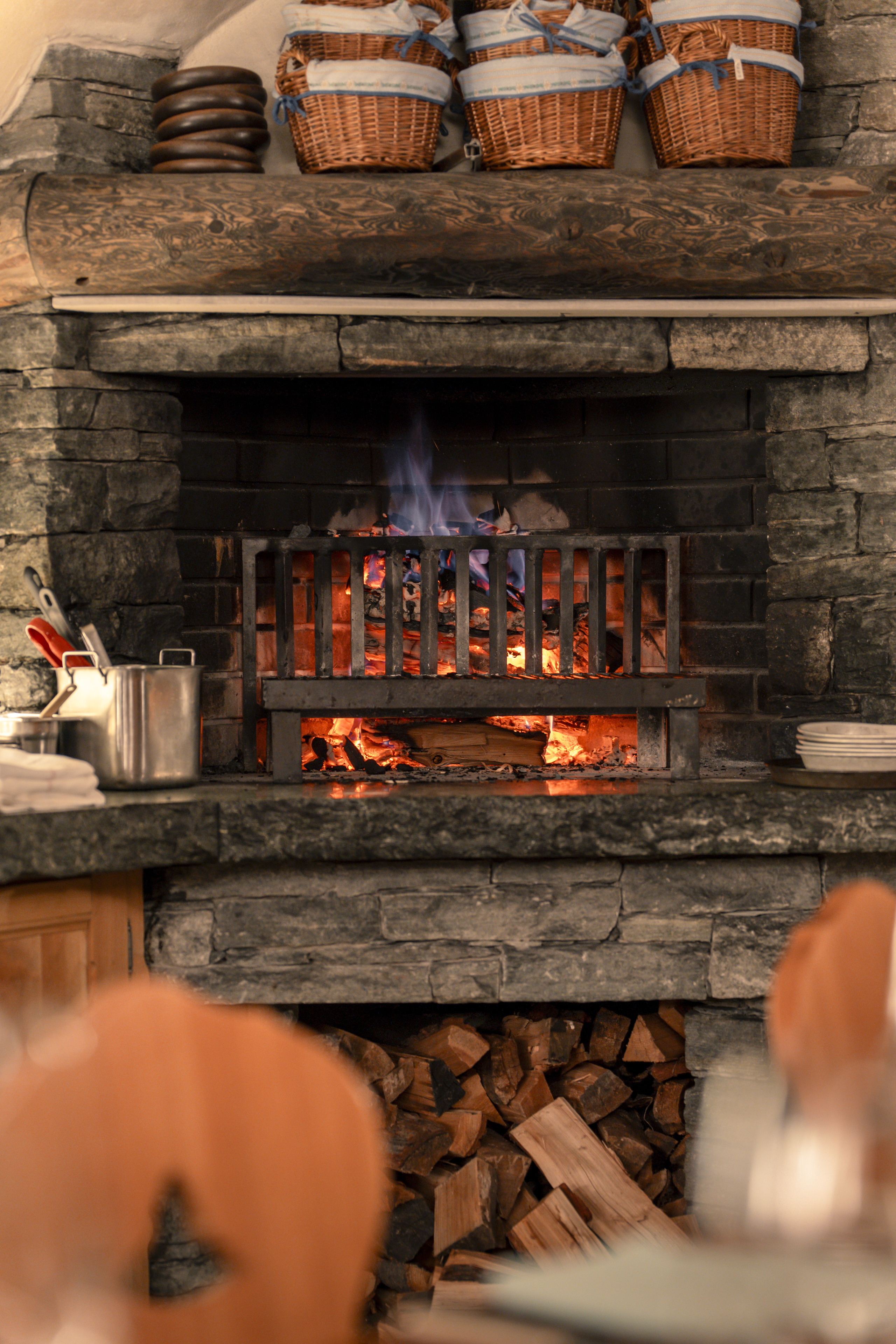 Cheminée en pierre du Restaurant Walliserkeller au Riffelalp Resort 2222m à Zermatt, hôtel de luxe 5 étoiles dans les Alpes suisses créant une ambiance chaleureuse pour savourer les spécialités valaisannes en hiver.