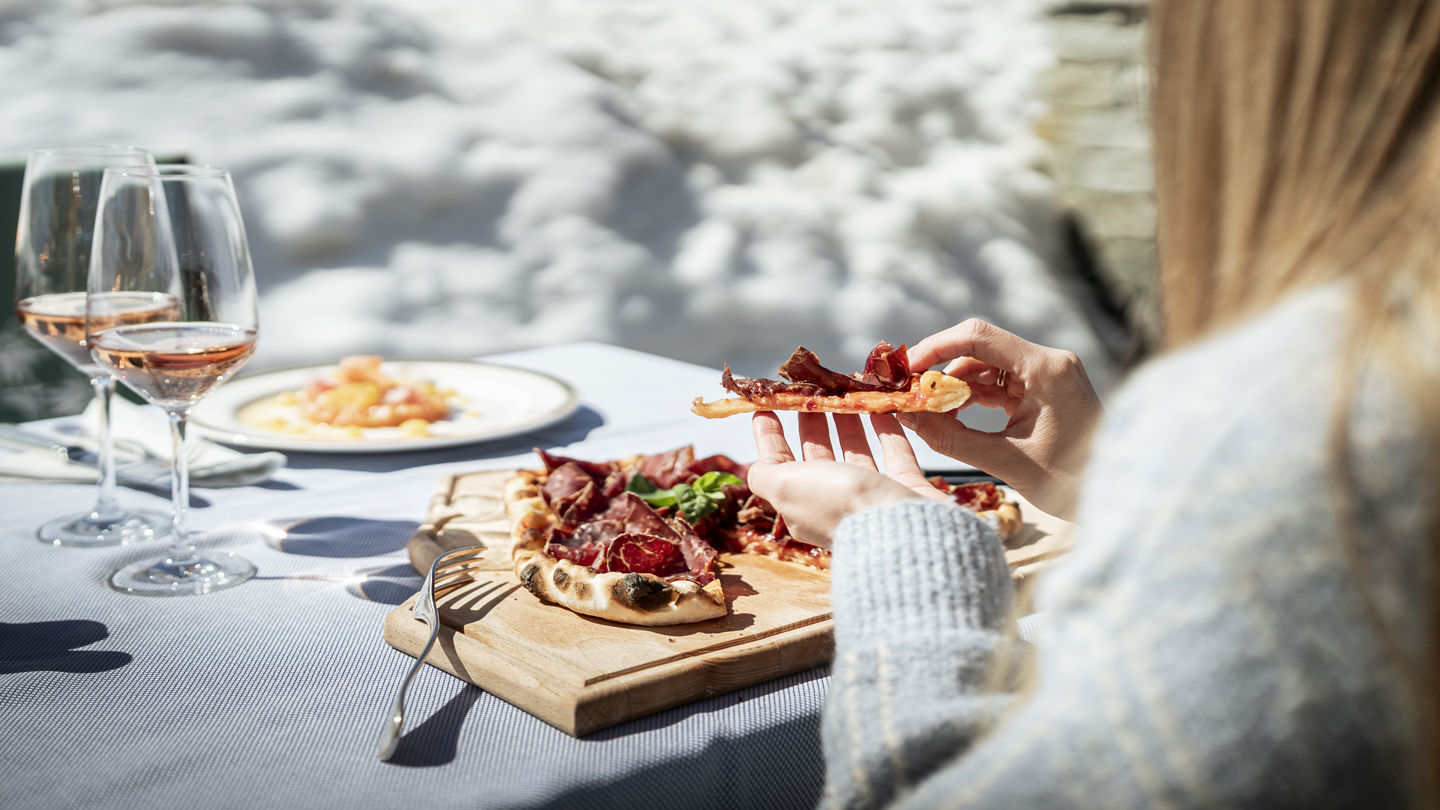 Planche pizza italienne servie sur la terrasse du Ristorante Al Bosco face aux montagnes au Riffelalp Resort 2222m à Zermatt, hôtel de luxe 5 étoiles dans les Alpes suisses offrant une gastronomie d'altitude et une vue exceptionnelle.
