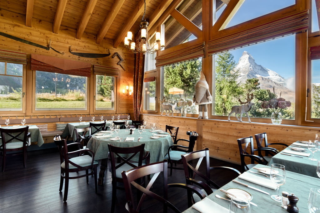 Salle panoramique du Ristorante Al Bosco au Riffelalp Resort 2222m au-dessus de Zermatt, hôtel de luxe 5 étoiles dans les Alpes suisses, offrant une cuisine italienne raffinée, des spécialités préparées avec des ingrédients alpins suisses et une vue exceptionnelle sur le Cervin.