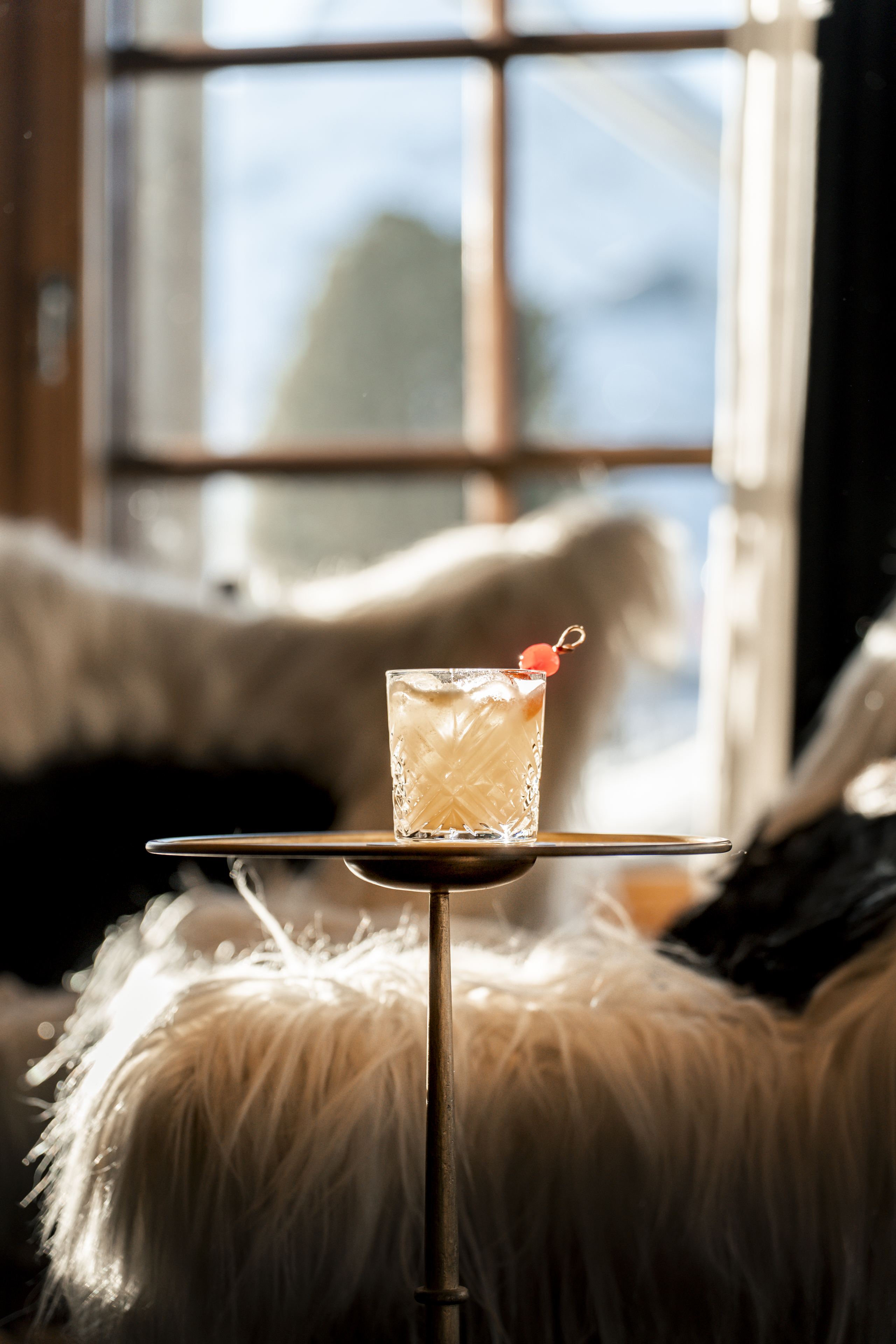 Cocktail signature dégusté près des fenêtres du Bar 2222m au Riffelalp Resort 2222m au-dessus de Zermatt, hôtel de luxe 5 étoiles dans les Alpes suisses associant mixologie, élégance et vue panoramique sur les Alpes.
